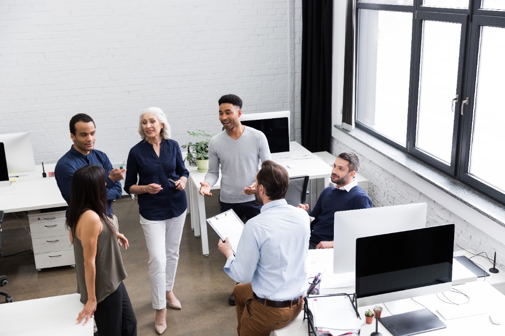 Équipe en réunion dans un bureau moderne, collaboration et atelier pratique sur l’IA au travail.
